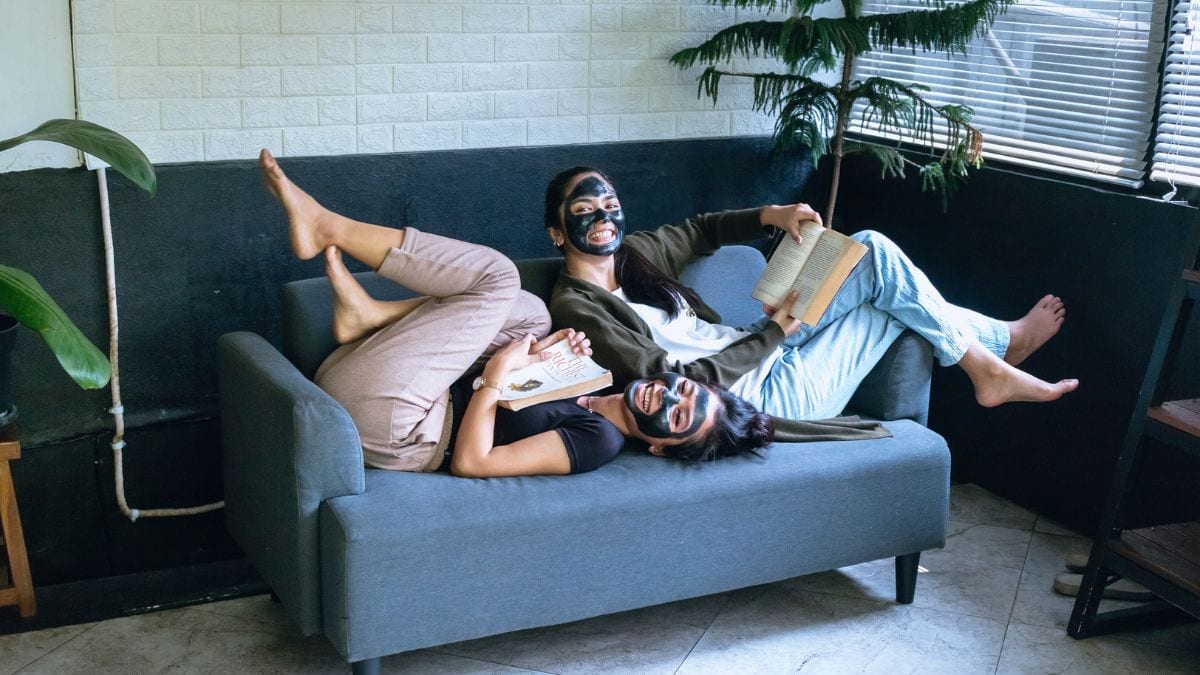 Girls laughing on a couch while wearing skincare face masks